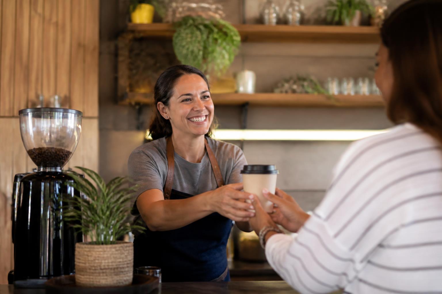 Barista usando programa de fidelidade digital Carimba em cafeteria moderna
